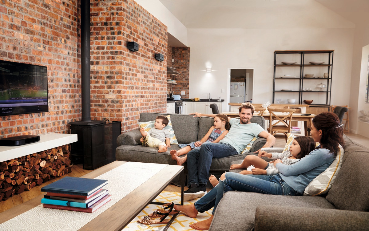 5-členná rodina sedí v obývacej izbe a pozerá sa na televíziu